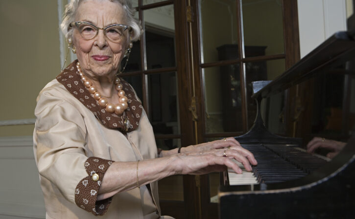 Senior woman playing piano, smiling, portrait
