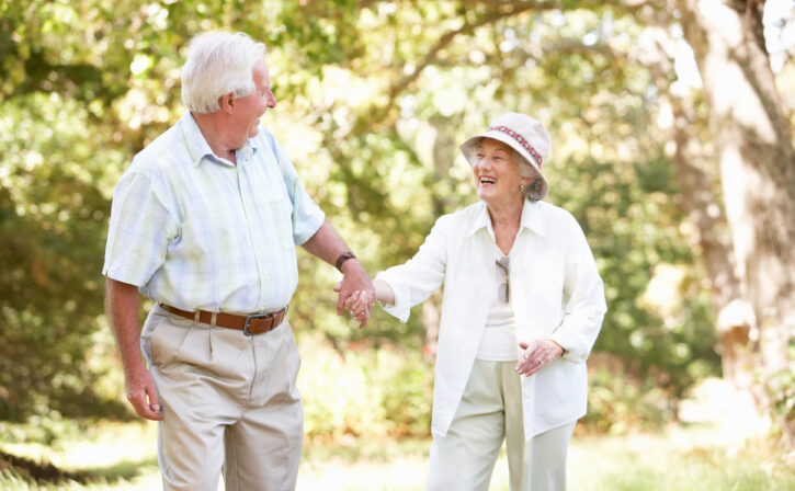 Senior Couple Walking In Park Holding Hands