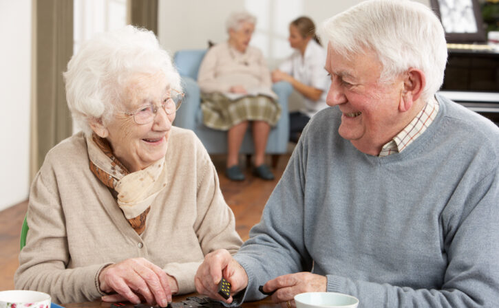 Senior Couple Playing Dominoes At Day Care Centre